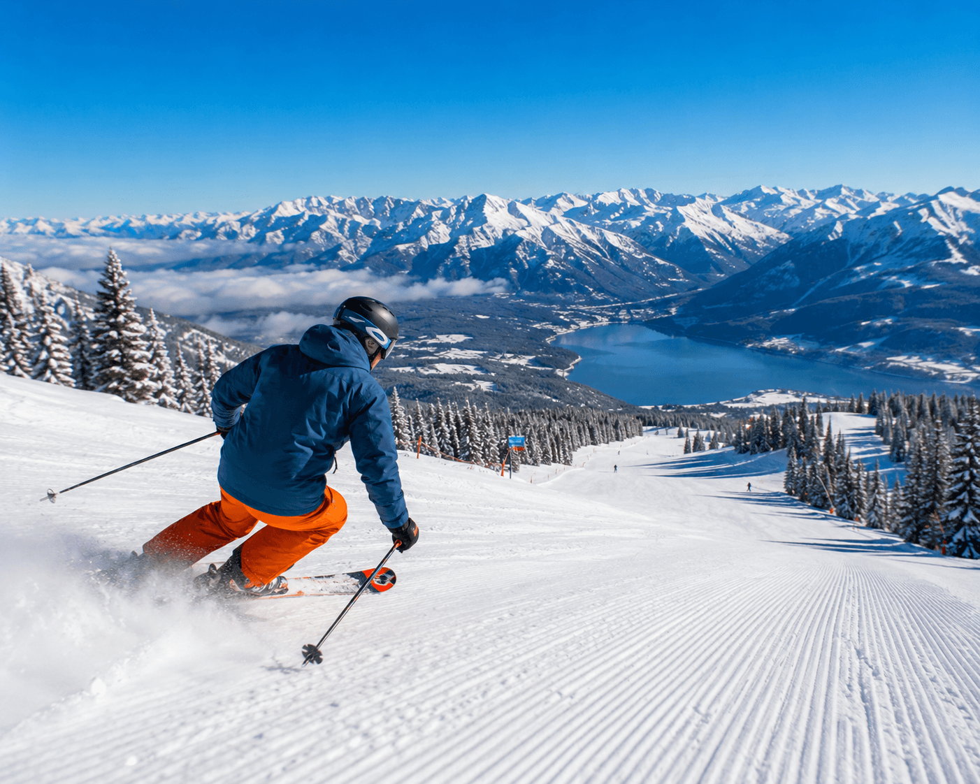 Skier descending a snowy slope above a mountain lake
